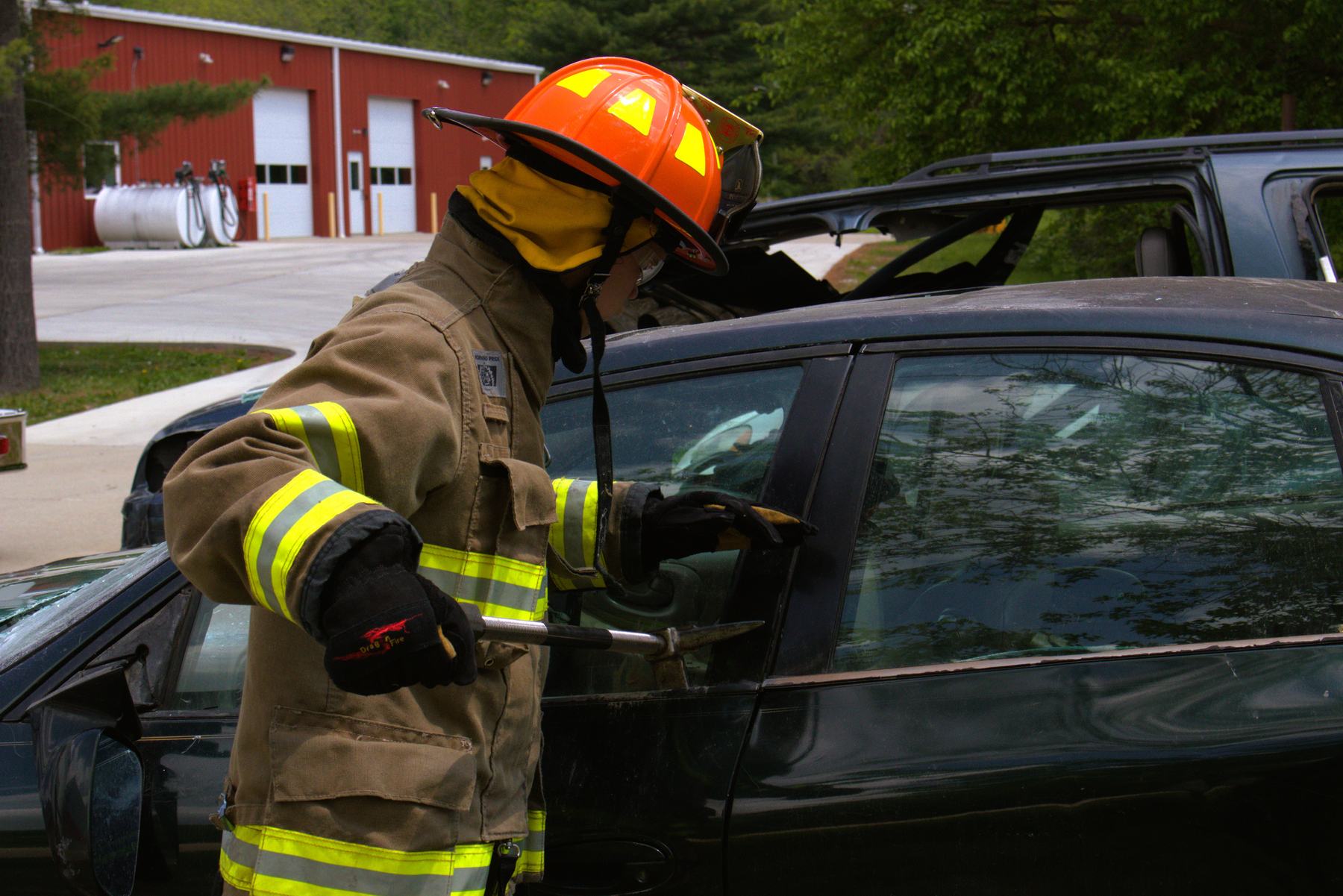 Firefighter forcing a car door with a Halligan bar during an extrication drill