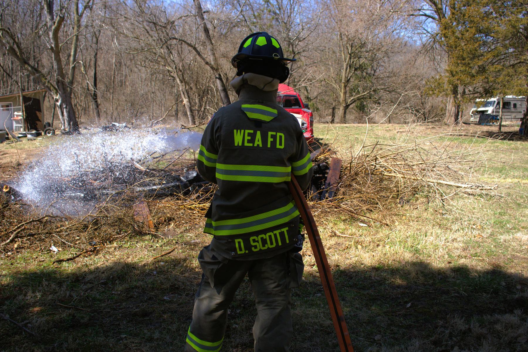 Firefighter putting water on a burning brush pile